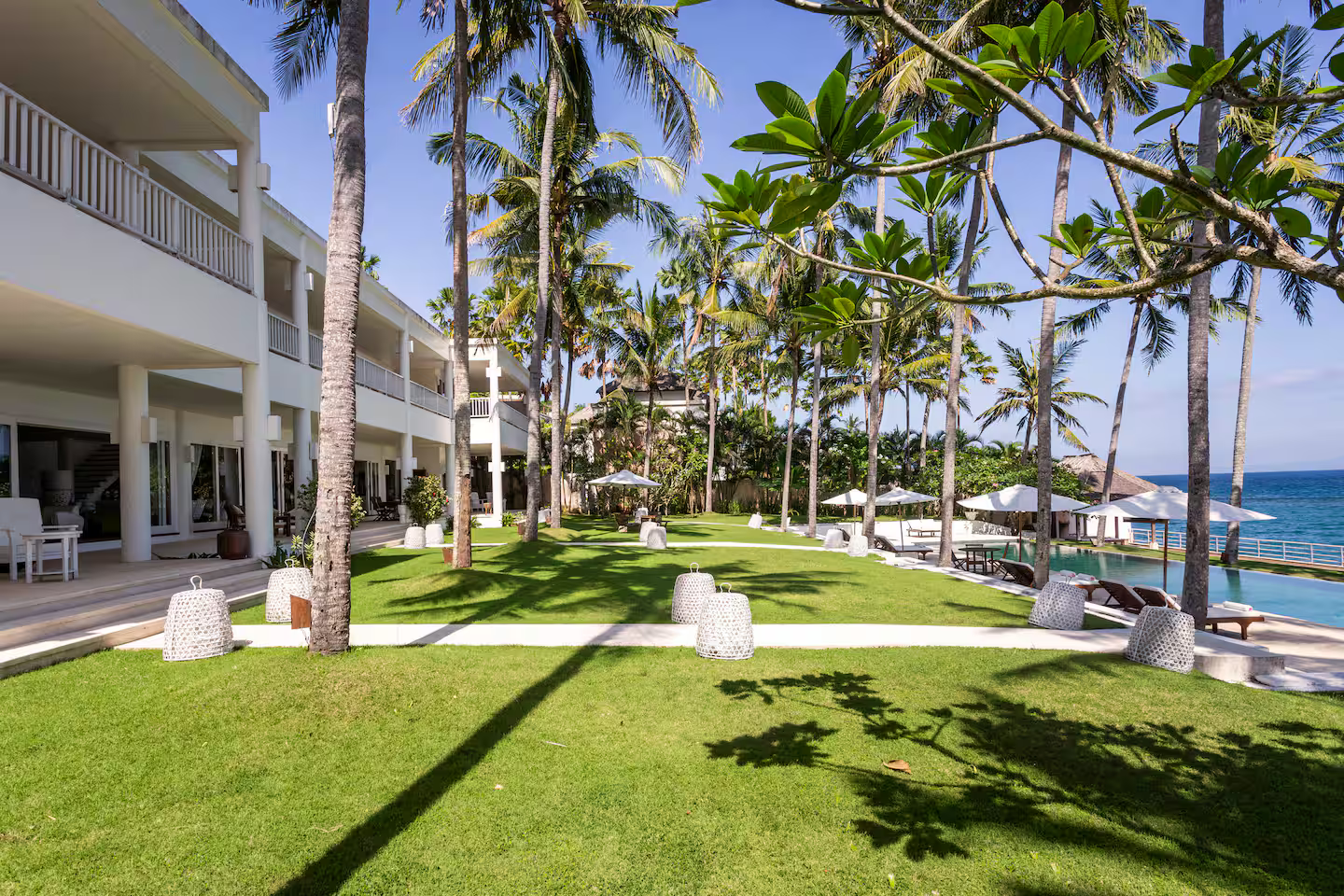 Villa and beachfront lawn shaded by palms