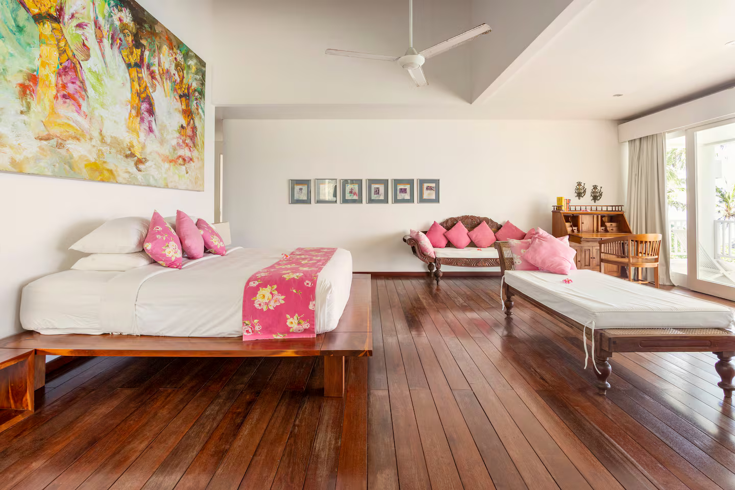 Airy bedroom with wooden flooring and colourful artwork