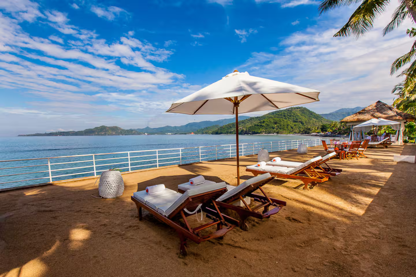 Beachfront terrace and loungers beneath a blue sky
