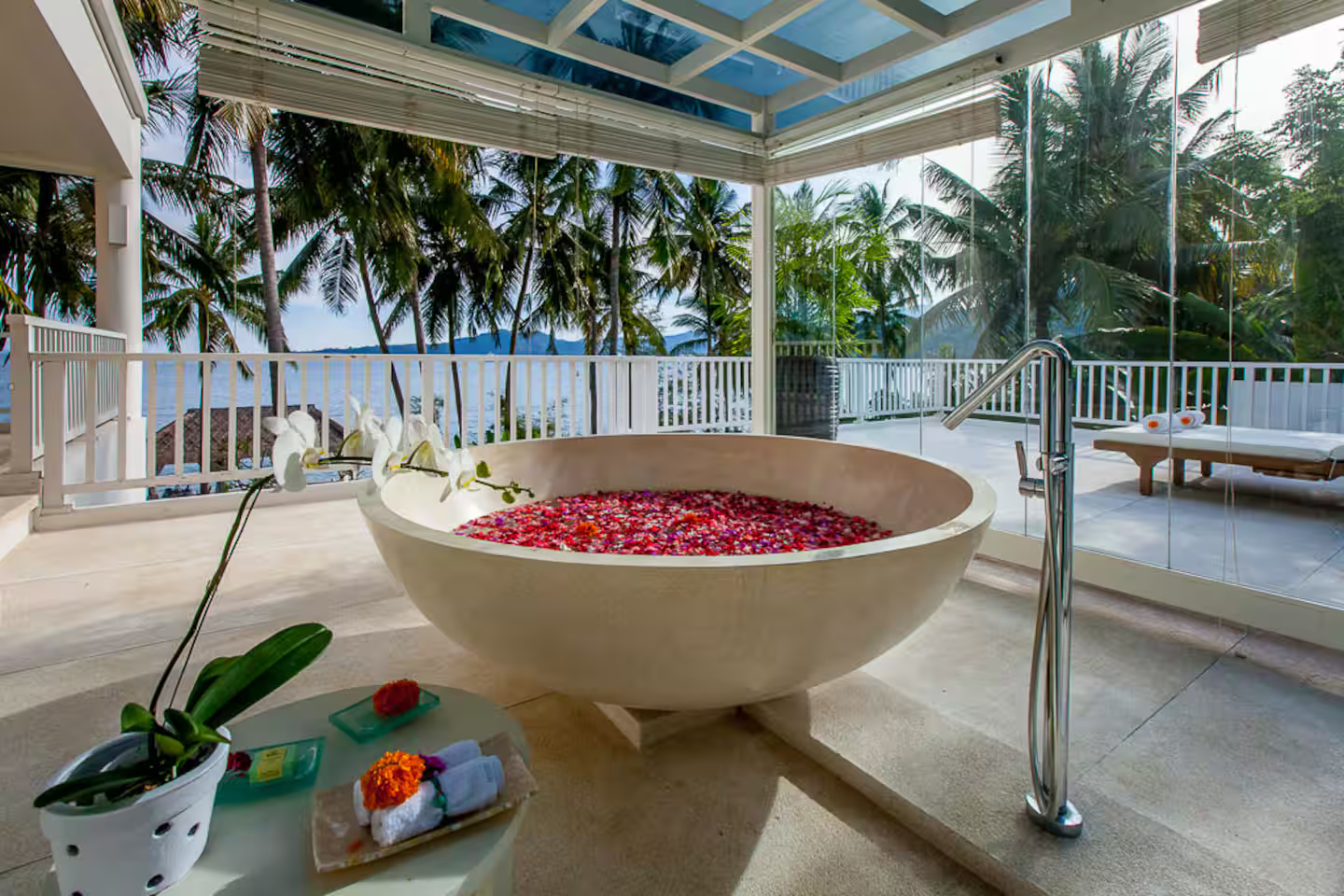Flower-filled bathtub in a glass-walled bathroom