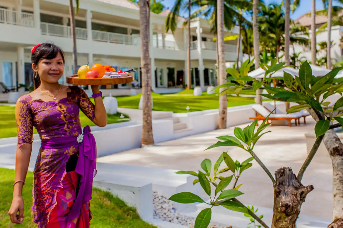 Villa staff member carrying a tray beside the garden