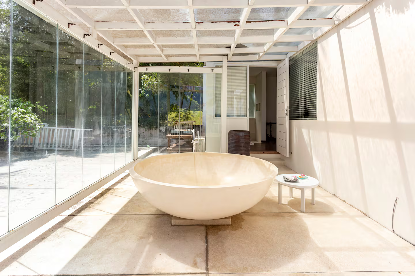 Round bathtub in a glass-walled garden bathroom