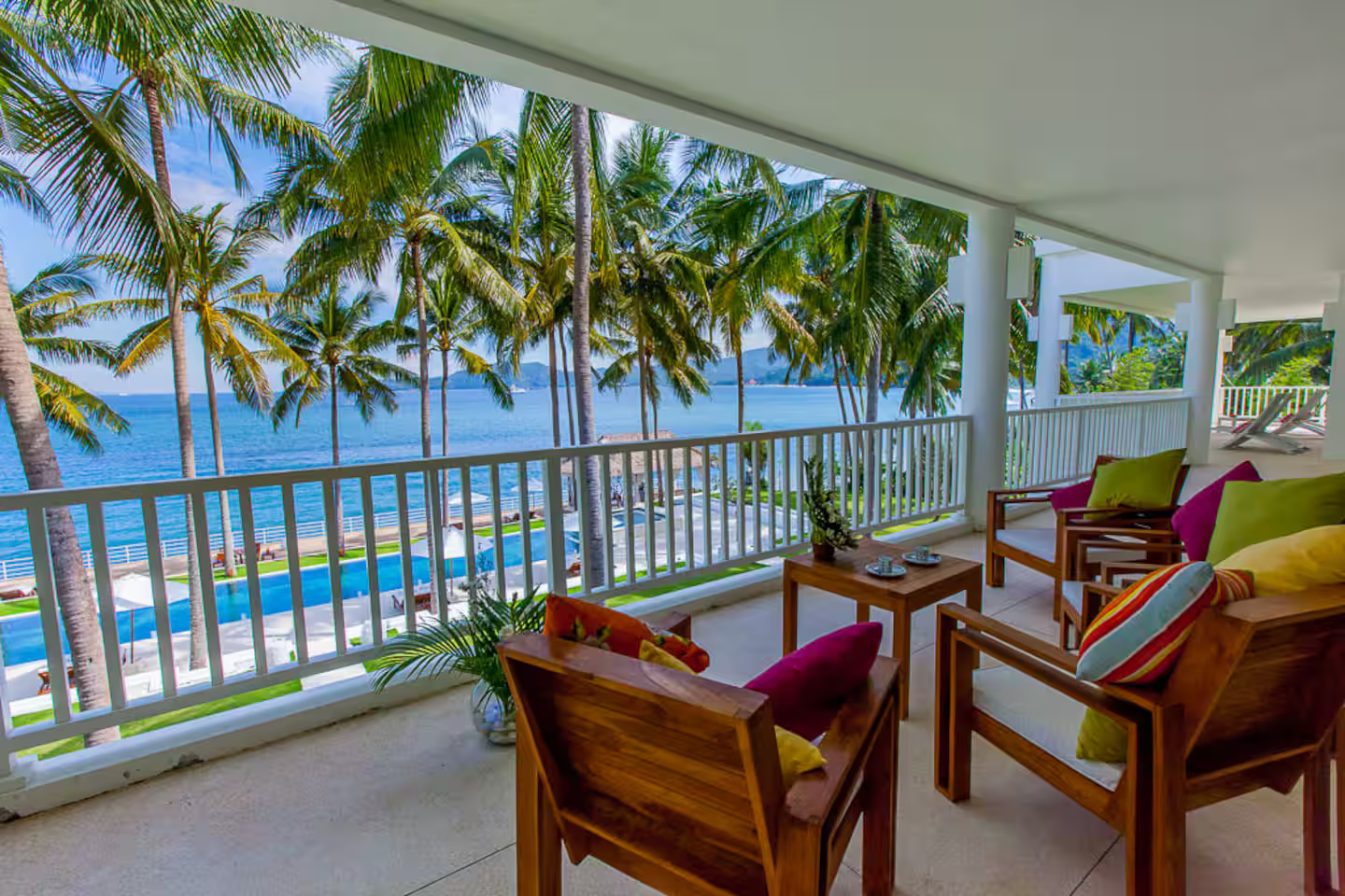 Seating on a covered veranda overlooking palms and sea