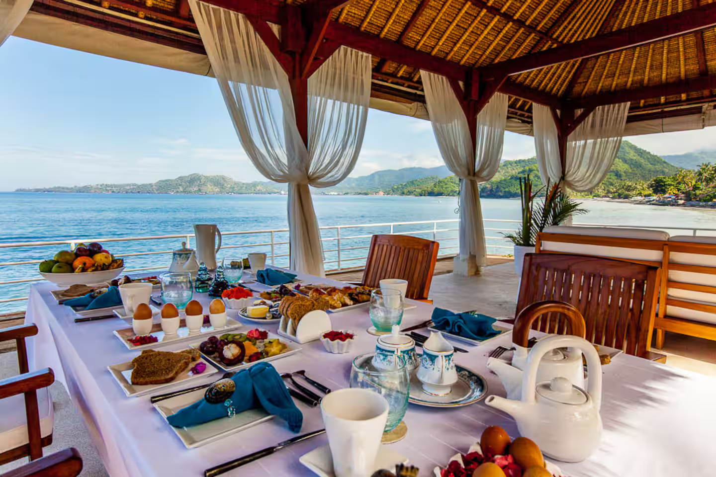 Dining table set with breakfast beneath a thatched pavilion
